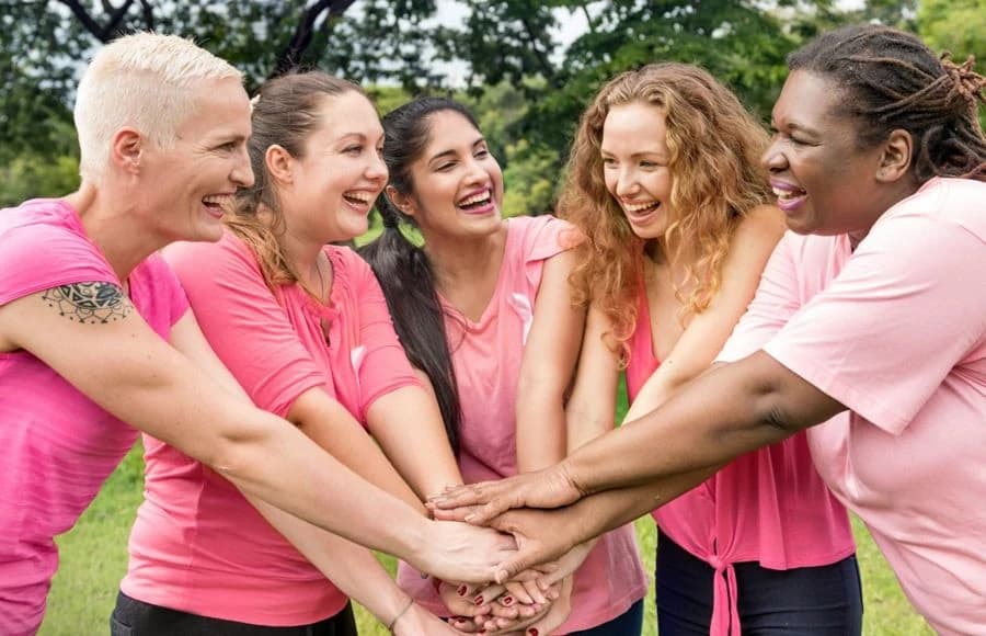 Women in pink shirts joining hands