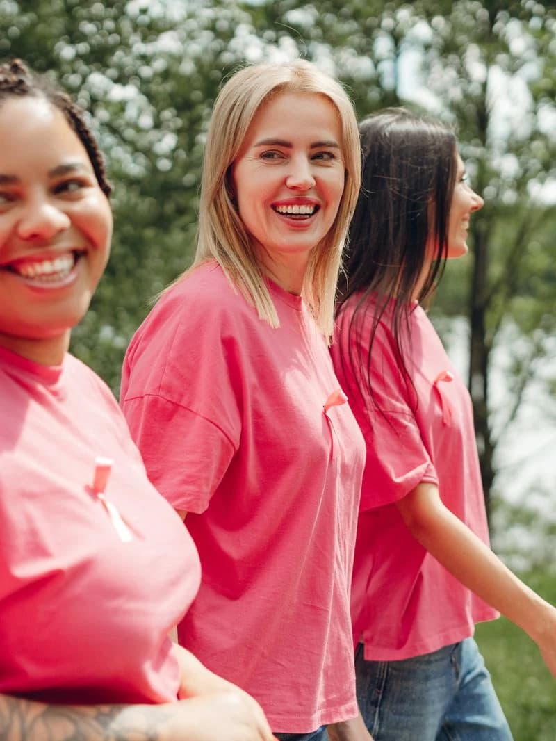 Three smiling women in pink T-shirts walking together